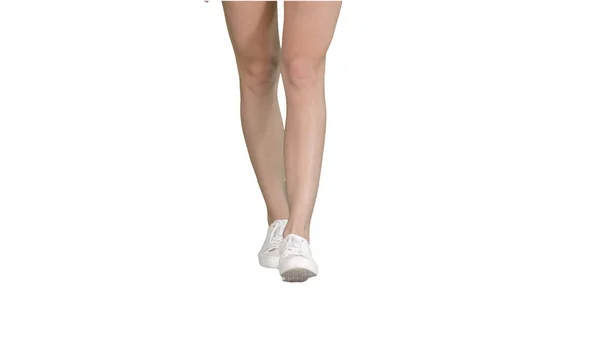 Female legs in white sneakers walking on white background. — Stock Photo, Image