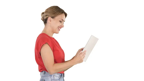 Жінка в повсякденному одязі за допомогою цифрового планшета, що йде на білому тлі . — стокове фото