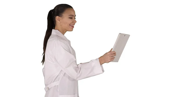 Jovem médico segurando tablet em suas mãos e fazendo chamada de vídeo no fundo branco. — Fotografia de Stock