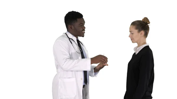 Άνδρας γιατρός προσφέρει φαρμακευτική αγωγή σε νεαρή γυναίκα σε λευκό φόντο. — Φωτογραφία Αρχείου