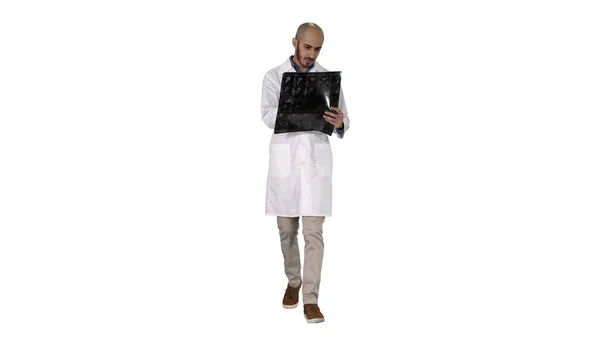 Doctor reviewing shoulder x-ray scan while walking on white background. — Stock Photo, Image