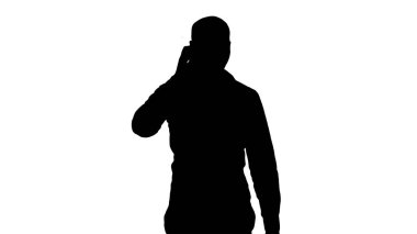 Siluet Genç Arap adam telefonda yürüyor, konuşuyor ve gülümsüyor.