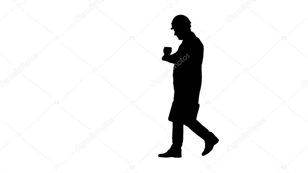 Silhouette Engineer walking in a rush and looking at his watch.