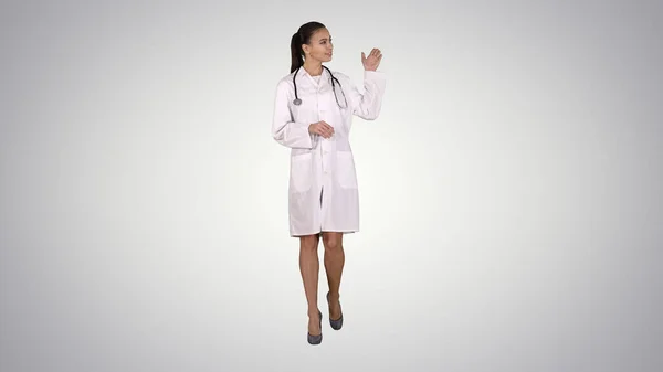 Vrouwelijke arts toont iets met de handen uitgebreid Presentatie op gradiënt achtergrond. — Stockfoto