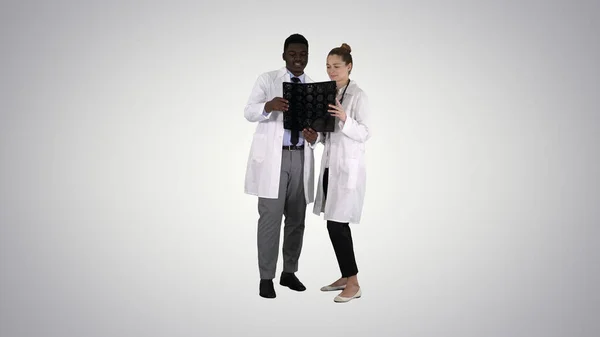 认真善良的女医生和非洲裔美国医生研究梯度背景下的脑部X光. — 图库照片