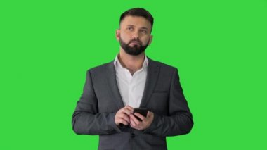 İş adamı telefonu yeşil ekranda düşünüyor ve kullanıyor, Chroma Key.
