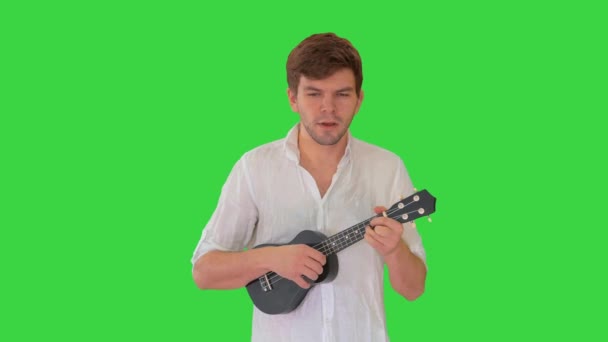 Joven jugando ukelele y firmando mientras camina en una pantalla verde, Chroma Key. — Vídeos de Stock