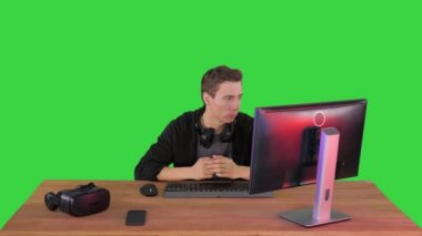 Ciddi bir oyuncu bilgisayarda oturmuş Yeşil Ekran 'da maç izliyor, Chroma Key.