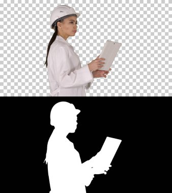 Tabletle yürüyen genç kadın mühendis çevredeki nesnelere bakıyor, Alfa Kanalı.
