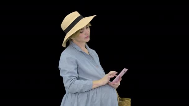 Happy pregnant woman in blue dress and hat using her smartphone, Alpha Channel — Stock Video