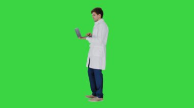 Beyaz önlüklü bir erkek doktor laptopunda Krom Anahtarlı yeşil ekranda video konferansı yapıyor..
