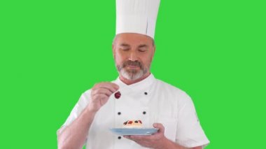 Pastanın üstüne vişne koyan aşçı Yeşil Ekran 'da pastaya krema koyuyor, Chroma Key.