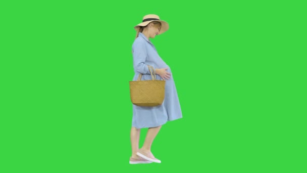 Piękna ciężarna kobieta w dużym kapeluszu chodząca i dotykająca brzucha na zielonym ekranie, Chroma Key. — Wideo stockowe