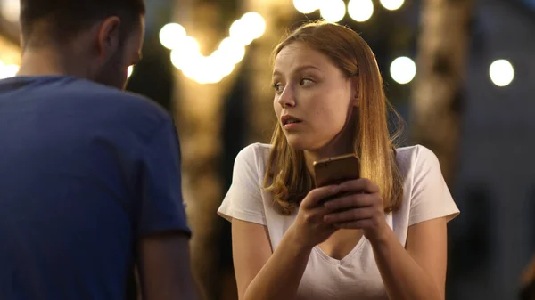 Verveeld mooi jong vrouw op slecht date met behulp van haar telefoon. — Stockfoto