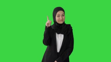 Türbanlı Arap iş kadını parmağını kaldırıyor ve yeşil ekran, krom anahtar onayıyla başını sallıyor..