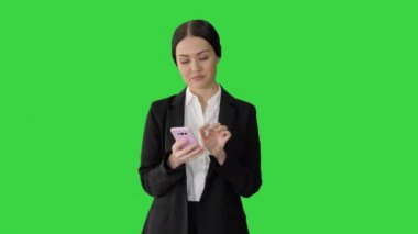 Takım elbiseli sıradan bir kadın telefonuyla yeşil ekranda mesaj atıyor, Chroma Key..