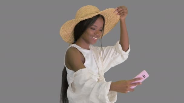 Hasır şapkalı gülümseyen Afrikalı Amerikalı kadın yürürken selfie çekiyor, Alpha Channel. — Stok video