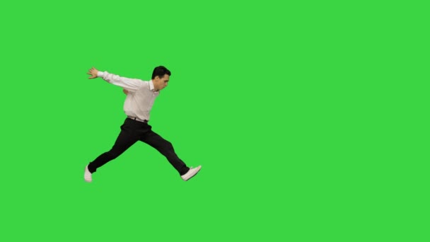 Jongeman gekleed in wit shirt en zwarte broek dansen break-dance en glimlachen naar de camera aan het einde op een groen scherm, Chroma Key. — Stockvideo