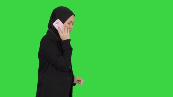 Vonzó modern muszlim nő sétál és beszél a mobiltelefon egy zöld képernyőn, Chroma Key. — Stock videók