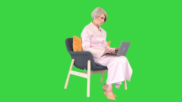 Donna anziana utilizzando il computer portatile mentre seduto su uno schermo verde, Chroma Key. — Video Stock