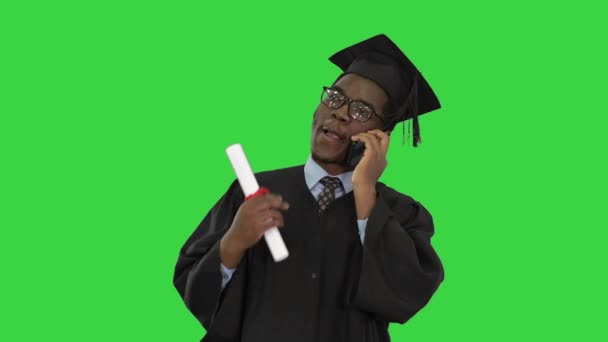 緑の画面で幸せなニュースを共有する電話で話して卒業ローブのアフリカ系アメリカ人男性学生を笑顔,クロマキー. — ストック動画