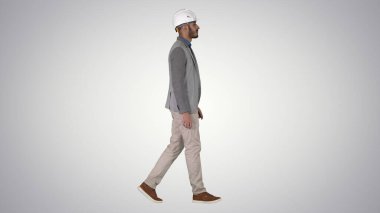 Beyaz miğferli mimar gradyan arkaplanda yürüyor.