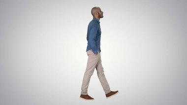 Model modelinden emin, elleri cebinde gradyan arka planda yürüyor..