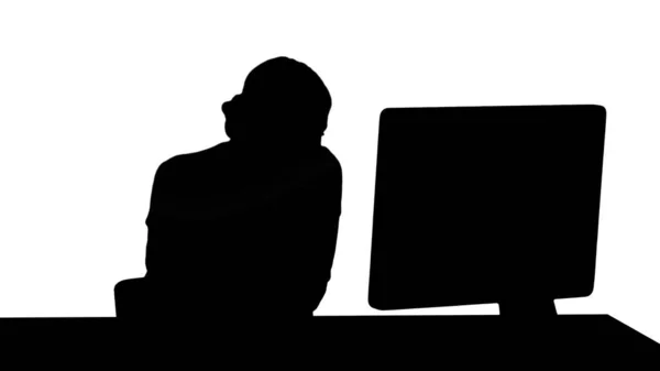 Silhouette Attraktive junge Frau, die am Handy telefoniert und lächelt, während sie an ihrem Arbeitsplatz im Büro sitzt und auf den Computer schaut. — Stockfoto