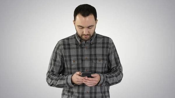 Genç adam yürüyor ve gradyan arka planda akıllı telefon kullanıyor. — Stok fotoğraf