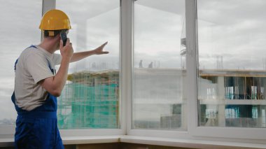 İnşaat alanındaki inşaat işçisi, vinç işi hakkında tavsiye vermek için meslektaşlarını arıyor..