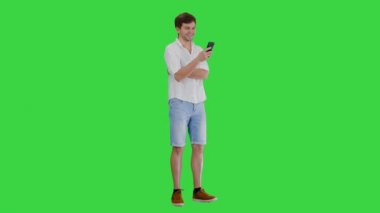 Yakışıklı genç adam akıllı telefonunu kullanıyor ve yeşil ekranda gülüyor, Chroma Key.