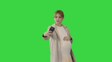 Mutlu genç hamile kadın yeşil ekranda selfie çekiyor, Chroma Key.