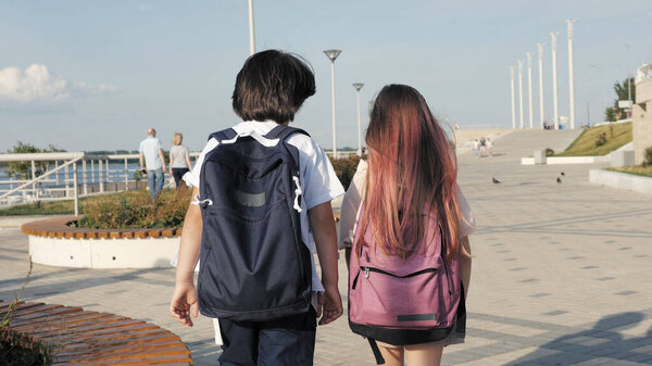 Two classmates walking with backpacks.