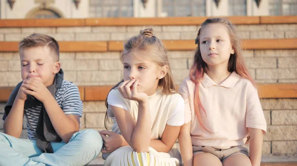 Cute boys and girls sitting in a park. — Stock Photo, Image