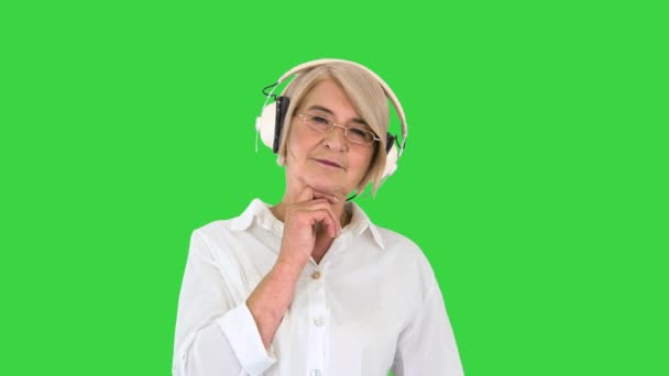 Vieille femme intelligente écoutant de la musique dans les écouteurs sur un écran vert, Chroma Key. — Video