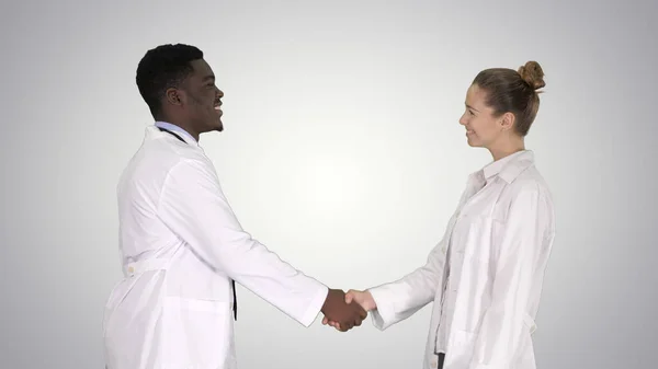 Nice to meet you Doctors meet and shake hands on gradient background.