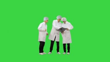 Beyaz cüppeli ve koruyucu şapkalı üç erkek doktor bilgisayarlı tomografi x-ray görüntüsüne bakıyor ve yeşil ekran Chroma Key 'deki kameraya bakıyor..