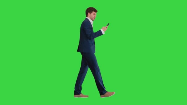 Serieuze zakenman met behulp van telefoon voice dial tijdens het lopen op een groen scherm, Chroma Key. — Stockvideo