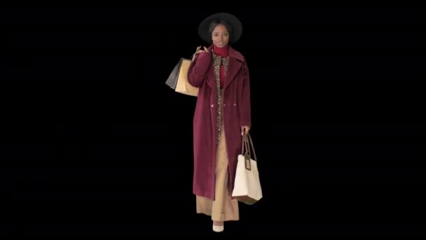Vacker afrikansk amerikansk modeflicka i rock och svart hatt promenader med shoppingväskor, Alpha Channel — Stockvideo