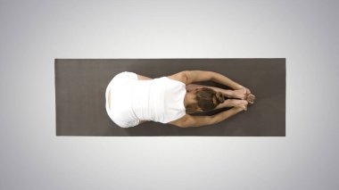 Genç sarışın kadın yoga yapıyor, öne eğilip egzersiz yapıyor, arka planda paschimottanasana pozu veriyor..