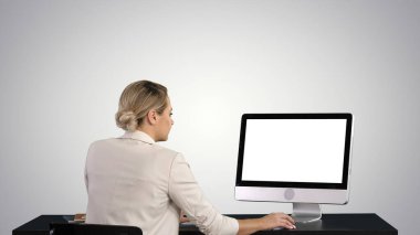 Ofiste çalışan kadın gradyan arka planda monitöre bakıyor..