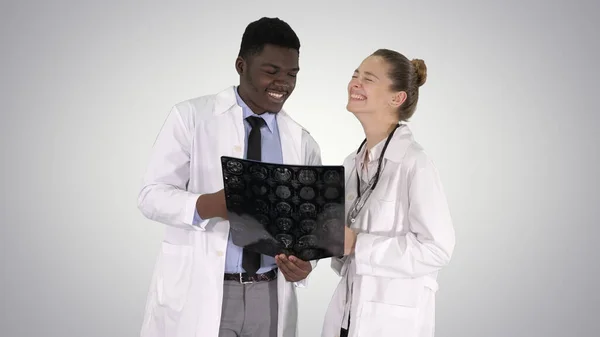 Γελαστοί γιατροί που μελετούν ακτίνες Χ σε βαθμιδωτό φόντο. — Φωτογραφία Αρχείου