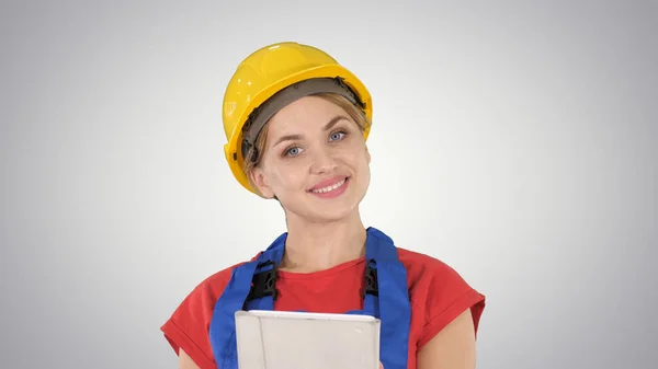 Young construction worker with tablet computer presenting something on gradient background. — Stock Photo, Image