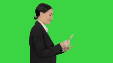 Yeşil Ekran 'da yürürken para sayan mutlu iş kadını, Chroma Key.
