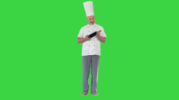 在绿色屏幕上拿着一瓶完美的葡萄酒，铬钥匙，微笑着的男厨师. — 图库视频影像