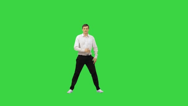 Молодой человек в белой рубашке и черных брюках прыгает в рамку и начинает танцевать перерыв глядя на камеру на зеленом экране, Chroma Key. — стоковое видео