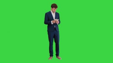 Mutlu iş adamı para sayıyor ve yeşil ekranda bir ceketin cebine sıkıştırıyor, Chroma Key..