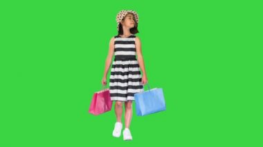 Asyalı bir alışveriş okulu kızı yeşil ekranda yürüyor ve gülümsüyor, Chroma Key.