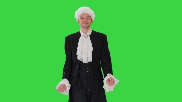 Mann in altmodischem Gehrock und weißer Perücke, der auf Manieren wandelt und auf einem Green Screen in die Kamera blickt, Chroma Key. — Stockvideo