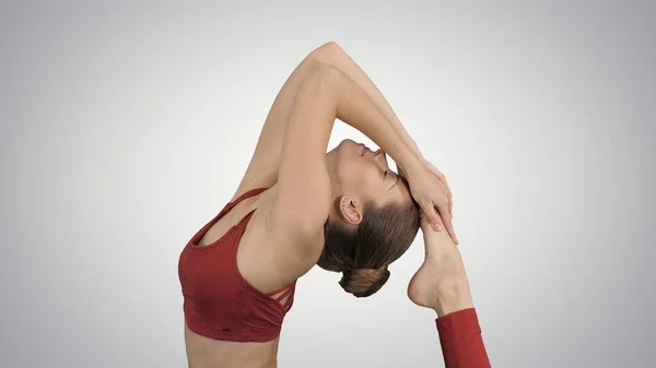 Bella giovane donna che fa esercizio di yoga Eka Pada Rajakapotasana Pose, One-Legged King Pigeon Postura su sfondo gradiente. — Foto Stock